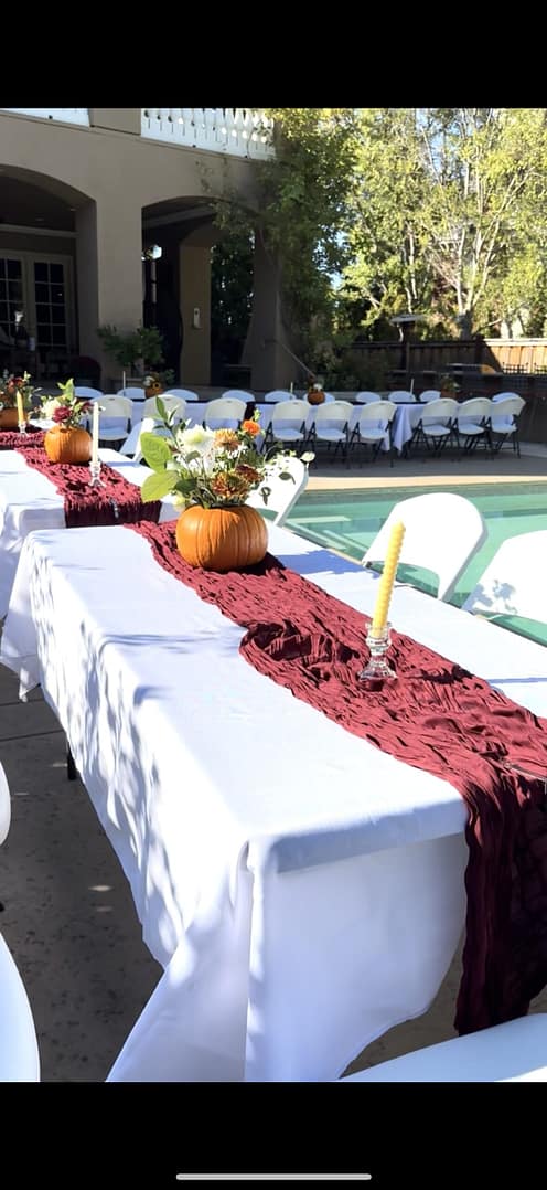 Customized Fall event by Mellow Events. Long tables with red runners and a pumpkin flower centerpiece